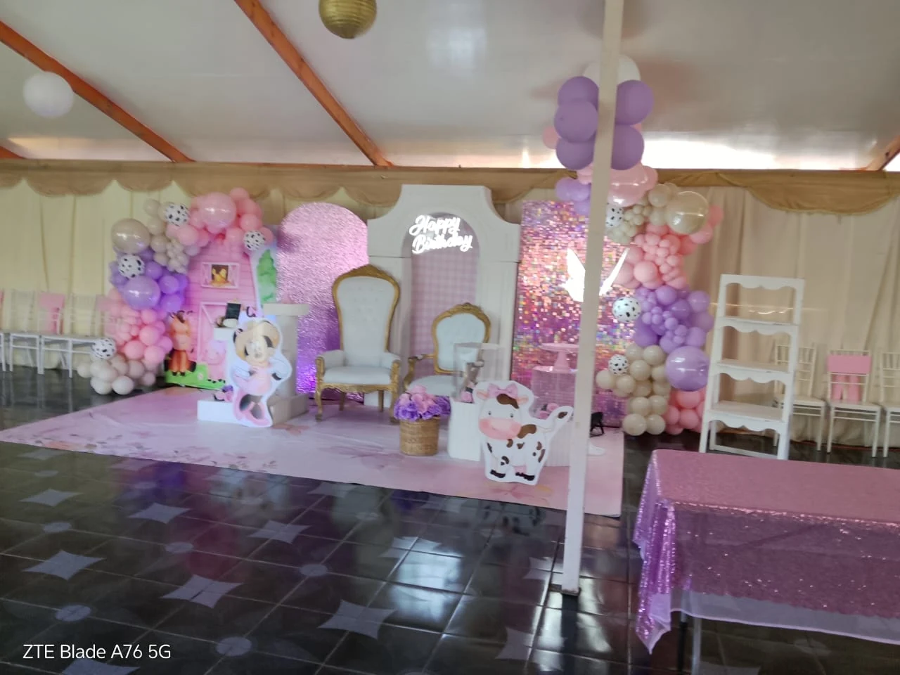 Montaje identificado por el cliente como baby shower, con globos rosas, lilas y blancos, figuras de Minnie y animales, sillas blancas y paneles brillantes.